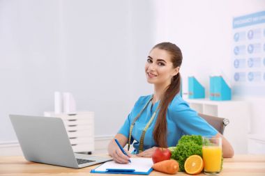 Young female nutritionist in her office clipart