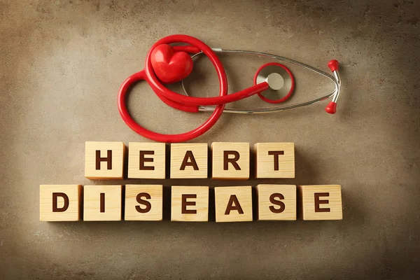 Текст HEART DISEASE з дерев'яних кубиків та стетоскопа на кольоровому фоні — стокове фото