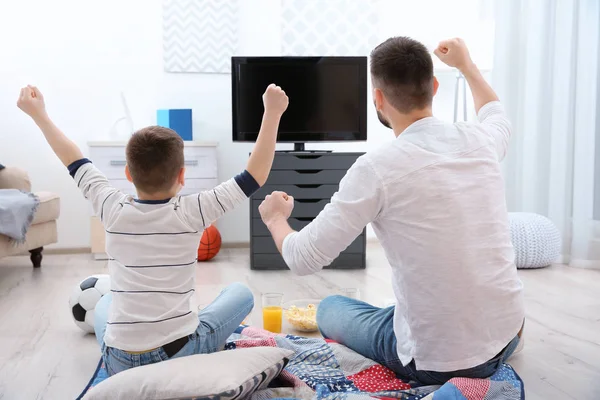 Pai e filho assistindo futebol na TV em casa — Fotografia de Stock