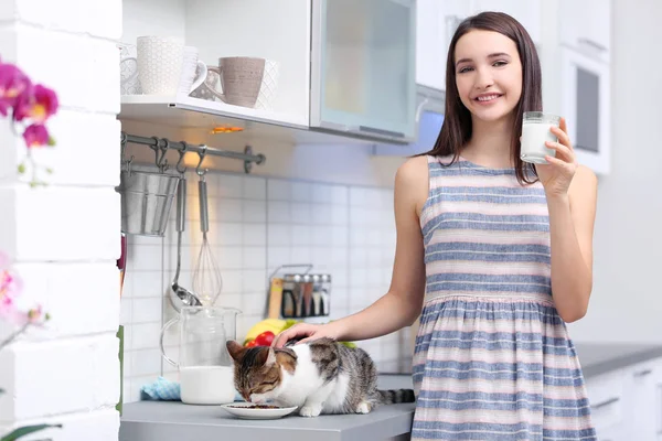 Piękna młoda kobieta karmienia ładny kot w kuchni — Zdjęcie stockowe
