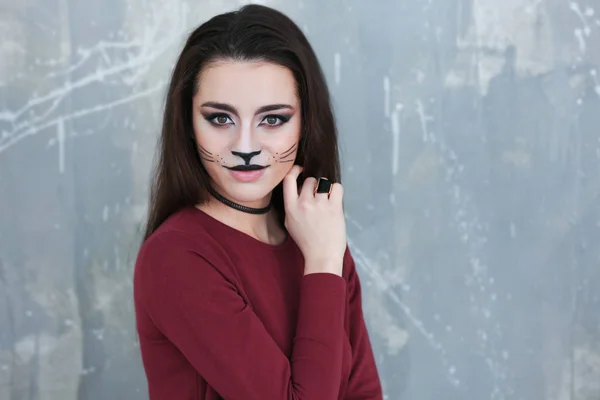 Beautiful young woman with cat makeup on grunge background — Stock Photo, Image