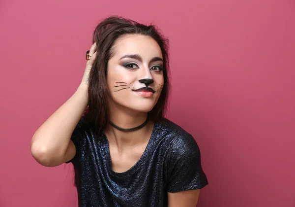 Schöne junge Frau mit Katze Make-up auf farbigem Hintergrund — Stockfoto