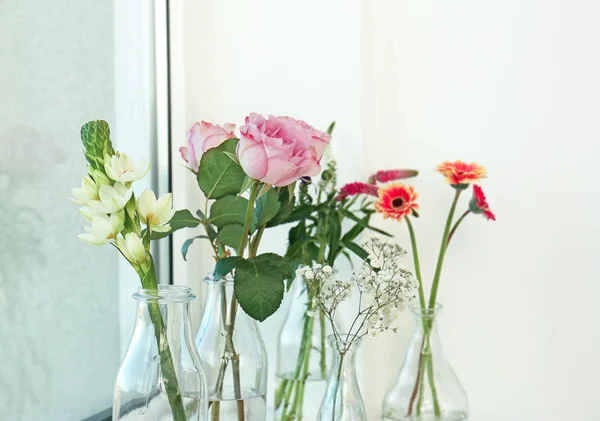 Glazen vazen met prachtige boeketten bloemen — Stockfoto