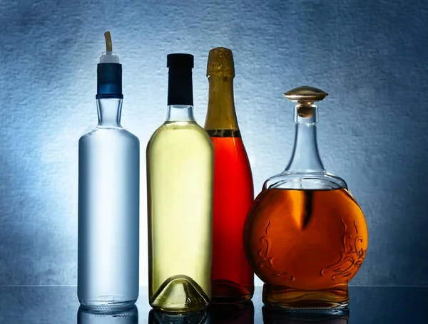 Diferentes botellas de vino y licores sobre fondo de color —  Fotos de Stock