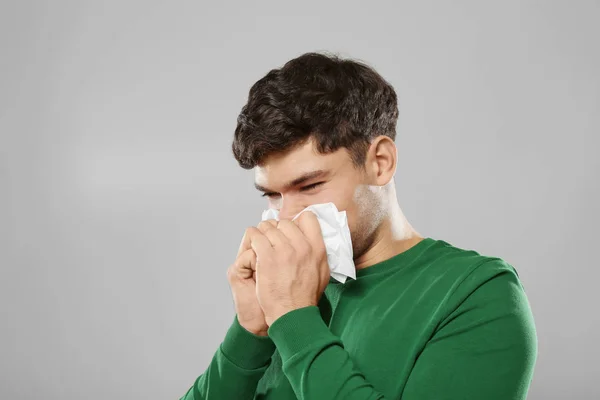 Jonge zieke man op grijze achtergrond — Stockfoto