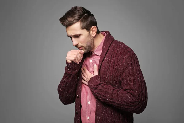 Joven tosiendo sobre fondo gris — Foto de Stock