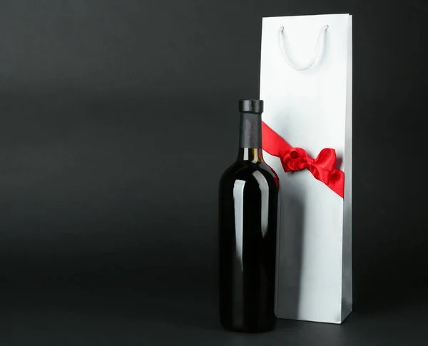 Κρασί μπουκάλι και δώρο τσάντα σε σκούρο φόντο — Φωτογραφία Αρχείου