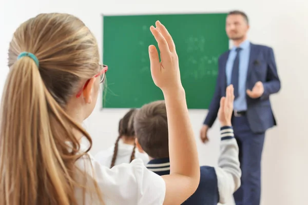Schoolmeisje hand opsteken voor antwoord tijdens de les — Stockfoto