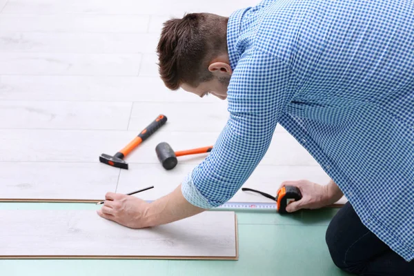 Uomo installazione pavimenti in laminato — Foto Stock
