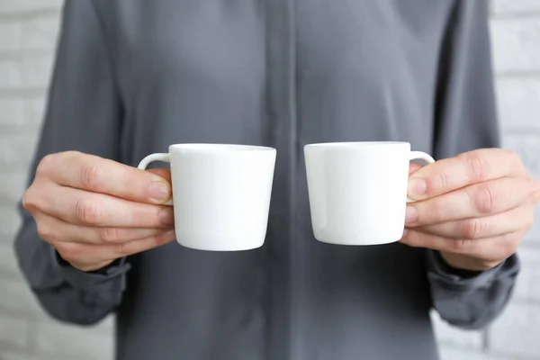 White cups in hands — Stock Photo, Image