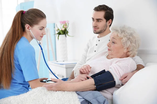 Nurse measuring woman's blood pressure with tonometer indoors — Stock Photo, Image