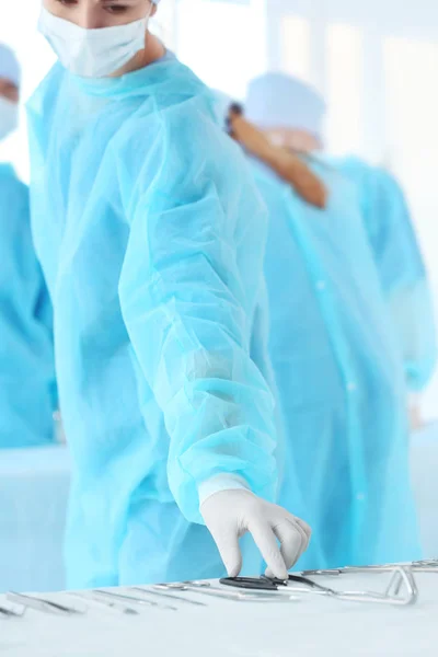 Dokter nemen instrument uit tabel tijdens operatie in kliniek — Stockfoto