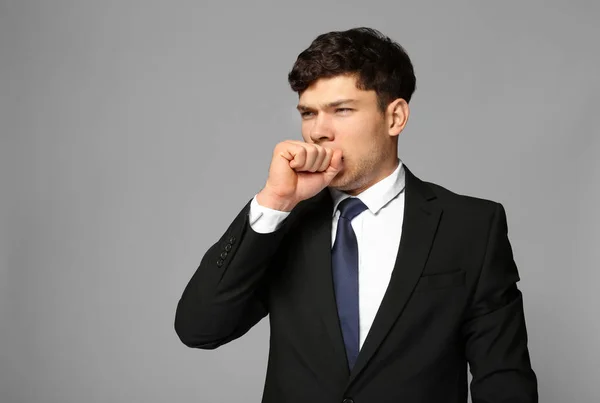 Joven enfermo de traje sobre fondo gris —  Fotos de Stock