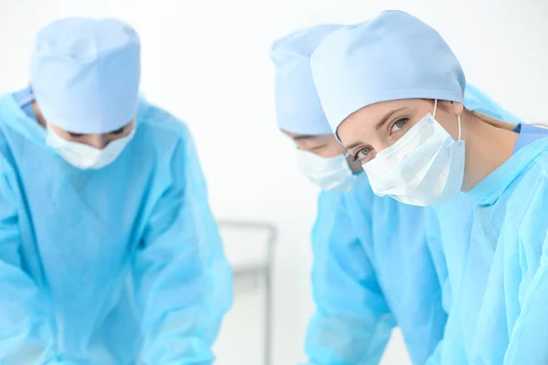 Beautiful young doctor with colleagues in clinic — Stock Photo, Image