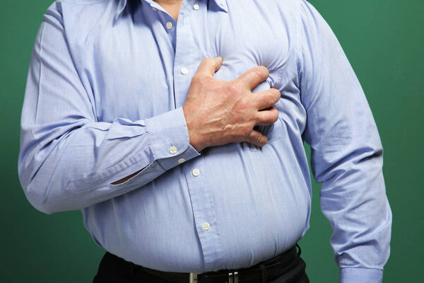Man with chest pain suffering from heart attack on color background