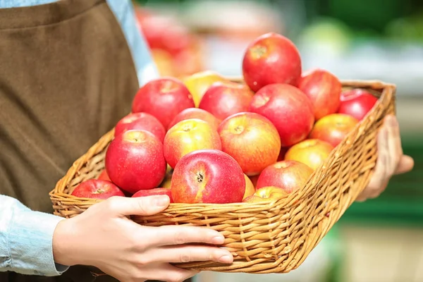 Female hands holding basket with apples — Stock Photo, Image