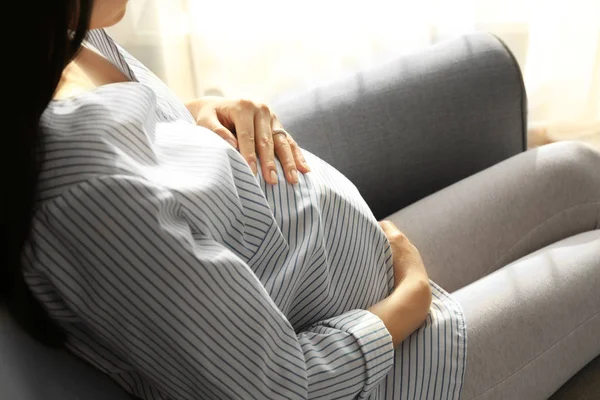 Beautiful pregnant woman sitting in arm-chair at home — Stock Photo, Image