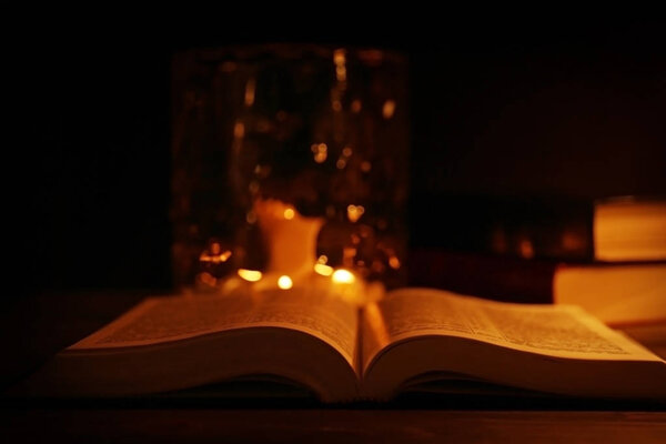 Bible and burning candles on background