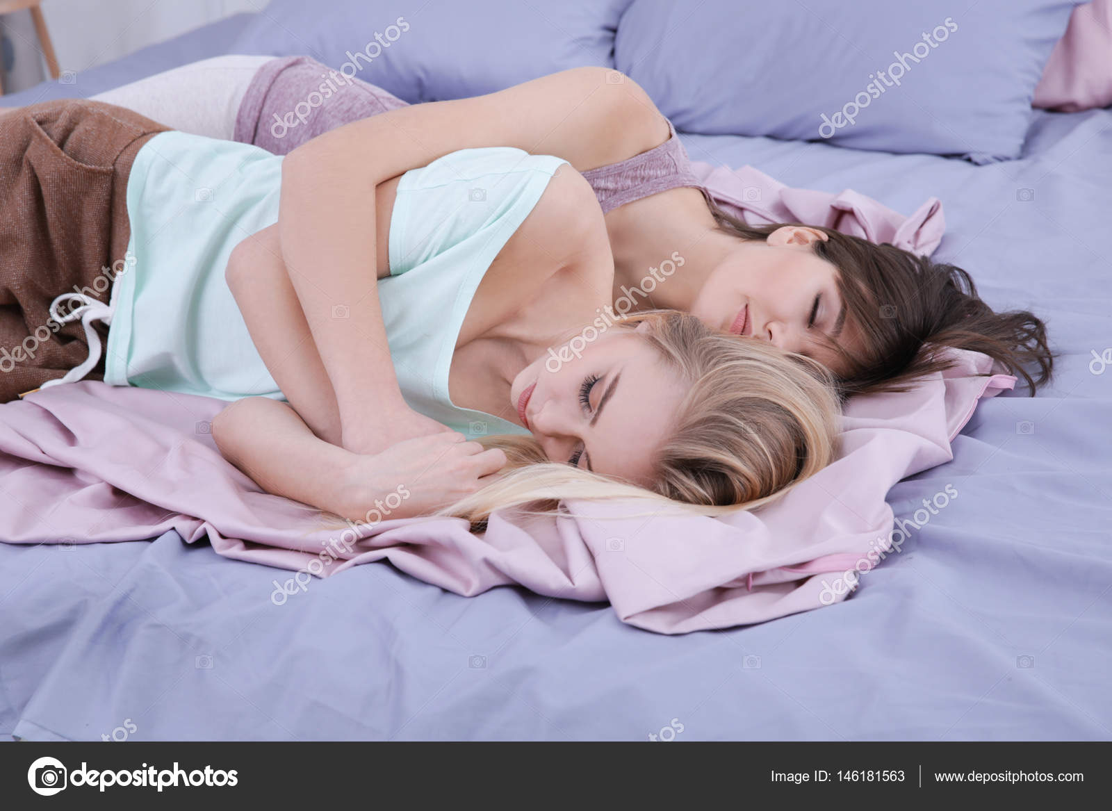 Lesbian couple sleeping on bed in bedroom by wavebreakmedia