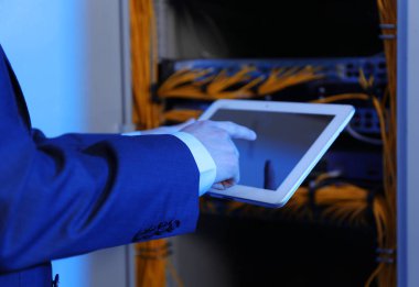Hands of young engineer with tablet computer in server room clipart