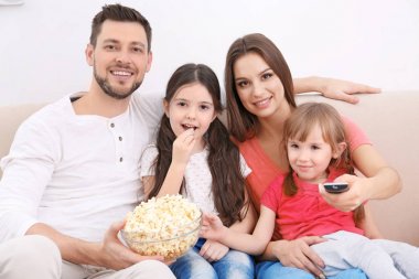 Mutlu bir aile evdeki kanepede televizyon izliyor.