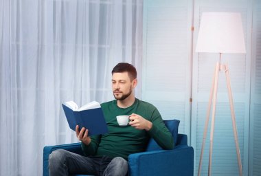 Genç adam kitap okuyor. 