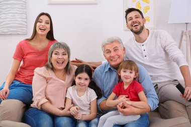 Mutlu bir aile evdeki kanepede televizyon izliyor.