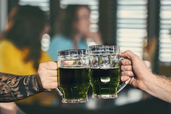 Hands of men with beer celebrating Saint Patrick's Day in pub