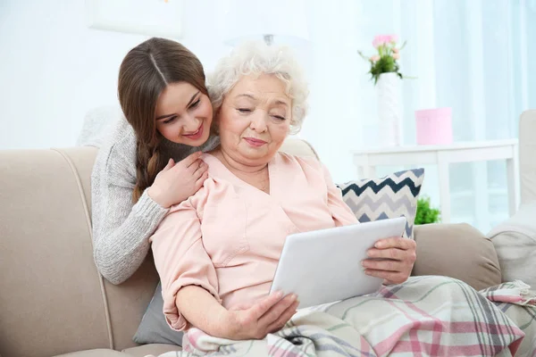 Piękna dziewczyna z babcia w domu za pomocą tabletu — Zdjęcie stockowe