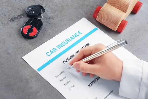 Hand filling in car insurance form — Stock Photo, Image