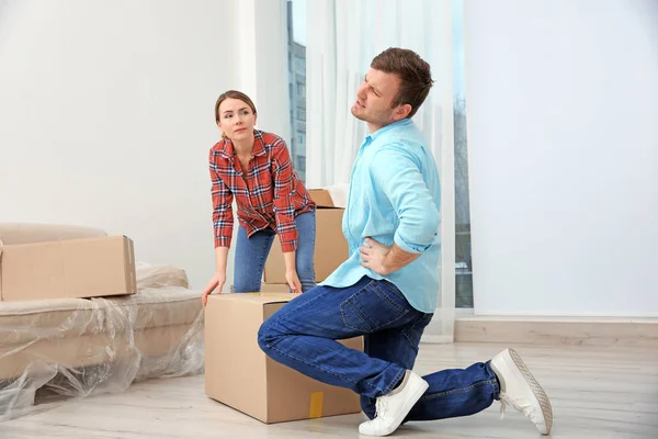 Man suffering from ache while moving box in room — Stock Photo, Image