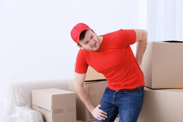 Jovem sofrendo de dor depois de mover caixa pesada — Fotografia de Stock