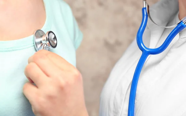 Female doctor listening patient's heart palpitations — Stock Photo, Image