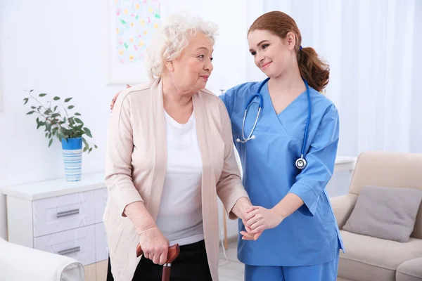 Verpleegkundige en ouderen vrouwen in lichte kamer — Stockfoto