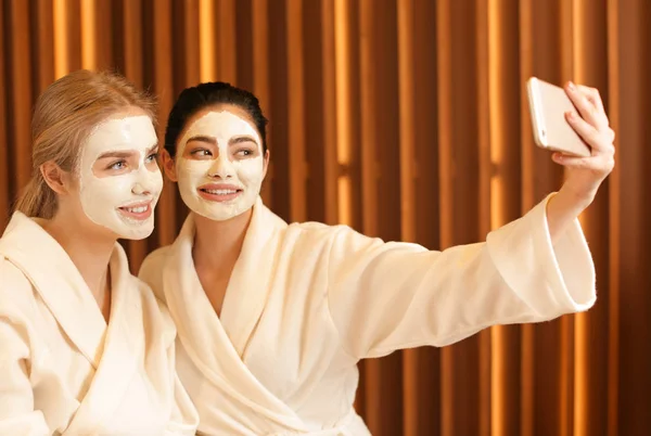 Mooie jonge vrouwen met maskers op gezichten selfie met spa salon — Stockfoto
