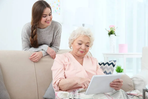 Krásná dívka s babičkou doma pomocí tabletu — Stock fotografie