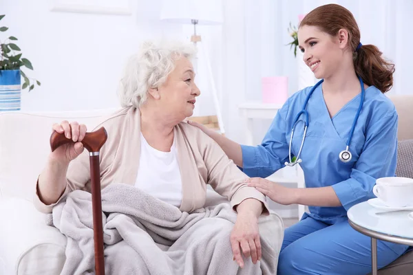 Nurse talking with elderly woman in light room — Stock Photo, Image