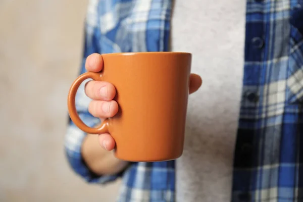 Taza naranja en blanco en la mano —  Fotos de Stock