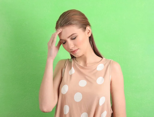 Piękna młoda kobieta cierpi na bóle głowy na tle kolor — Zdjęcie stockowe