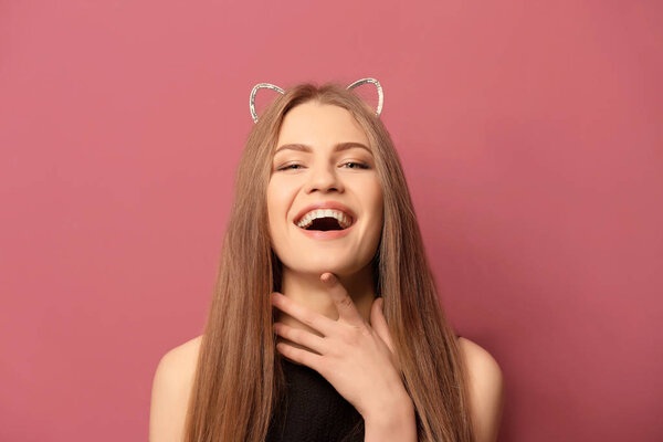 Beautiful young woman with cat ears on color background