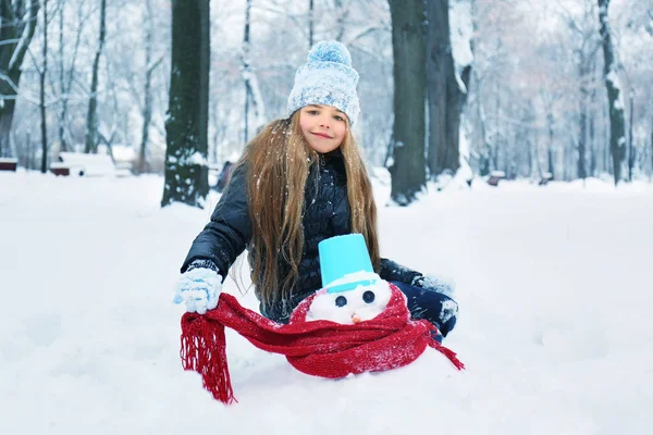 冬の公園で雪だるまを作ってかわいい女の子 — ストック写真