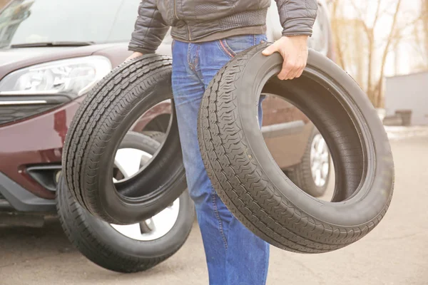 Homem carregando dois pneus ao ar livre — Fotografia de Stock