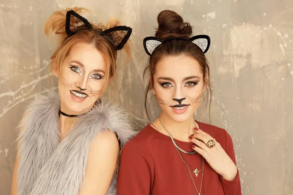 Vackra unga kvinnor med katt makeup och öron på grunge bakgrund — Stockfoto