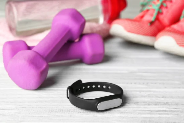 Fitness tracker and sportive equipment on light wooden background — Stock Photo, Image