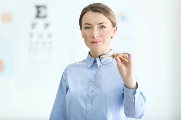 Vrouw met brillen in hand op achtergrond wazig — Stockfoto