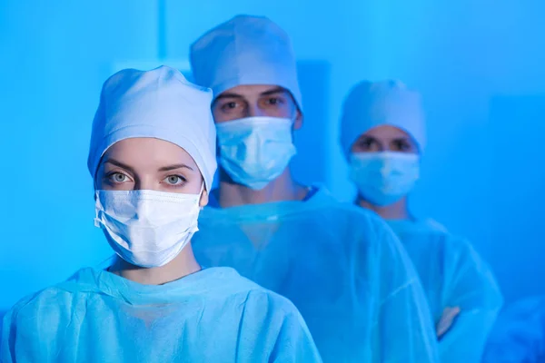 Portrait of young surgeon with blurred colleagues on background in modern clinic — Stock Photo, Image