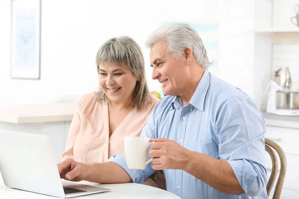 Cuplu de vârstă mijlocie cu laptop în bucătărie — Fotografie, imagine de stoc