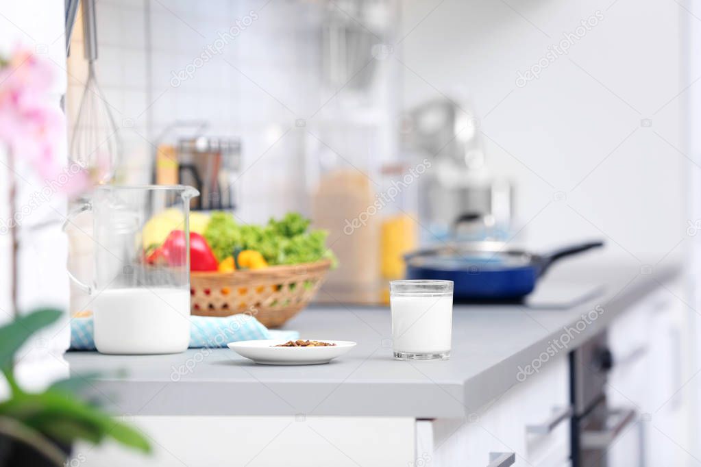 Plate with dry food and milk prepared for cat on kitchen counter