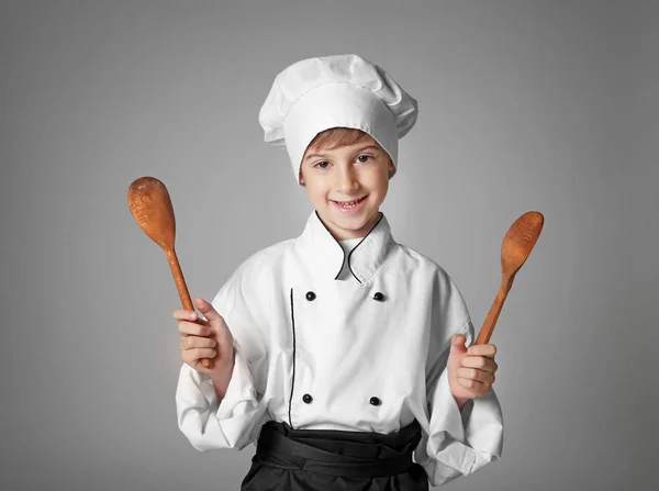 Хлопчик у кулінарній уніформі тримає посуд — стокове фото