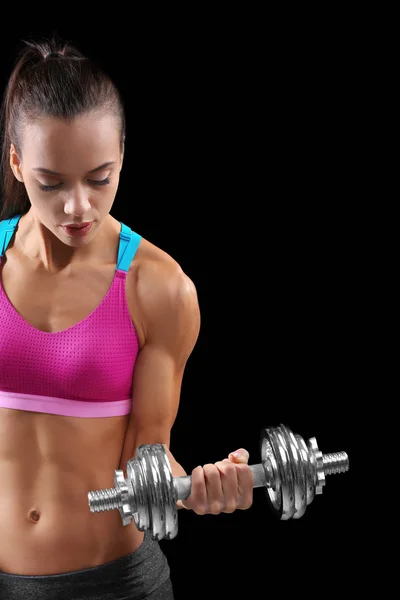 Deportiva joven con mancuerna sobre fondo negro — Foto de Stock